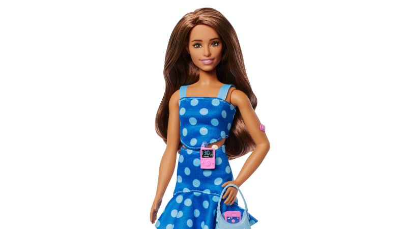 Barbie doll with type 1 diabetes holding insulin pump and CGM devices