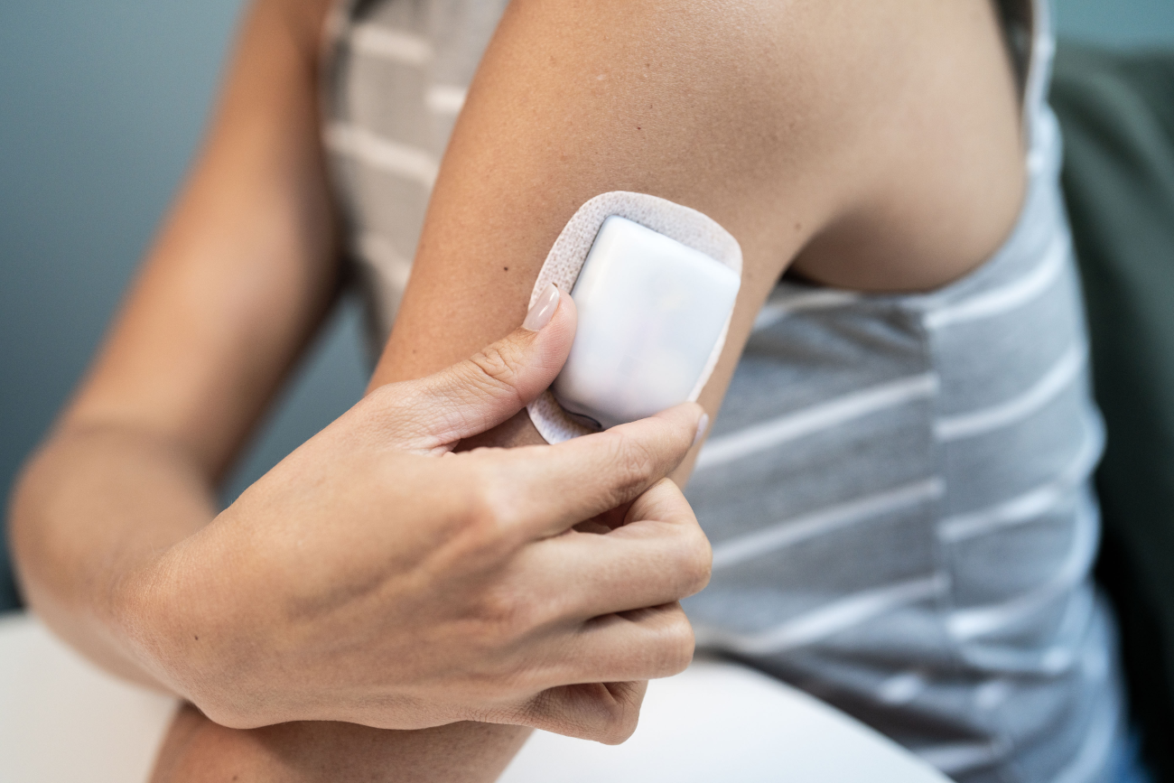 A person holding their arm wrapped with a white bandage, showcasing the Omnipod 5 insulin pump device, highlighting the partnership between Insulet and Marvel for a comic book featuring a superhero with Type 1 diabetes